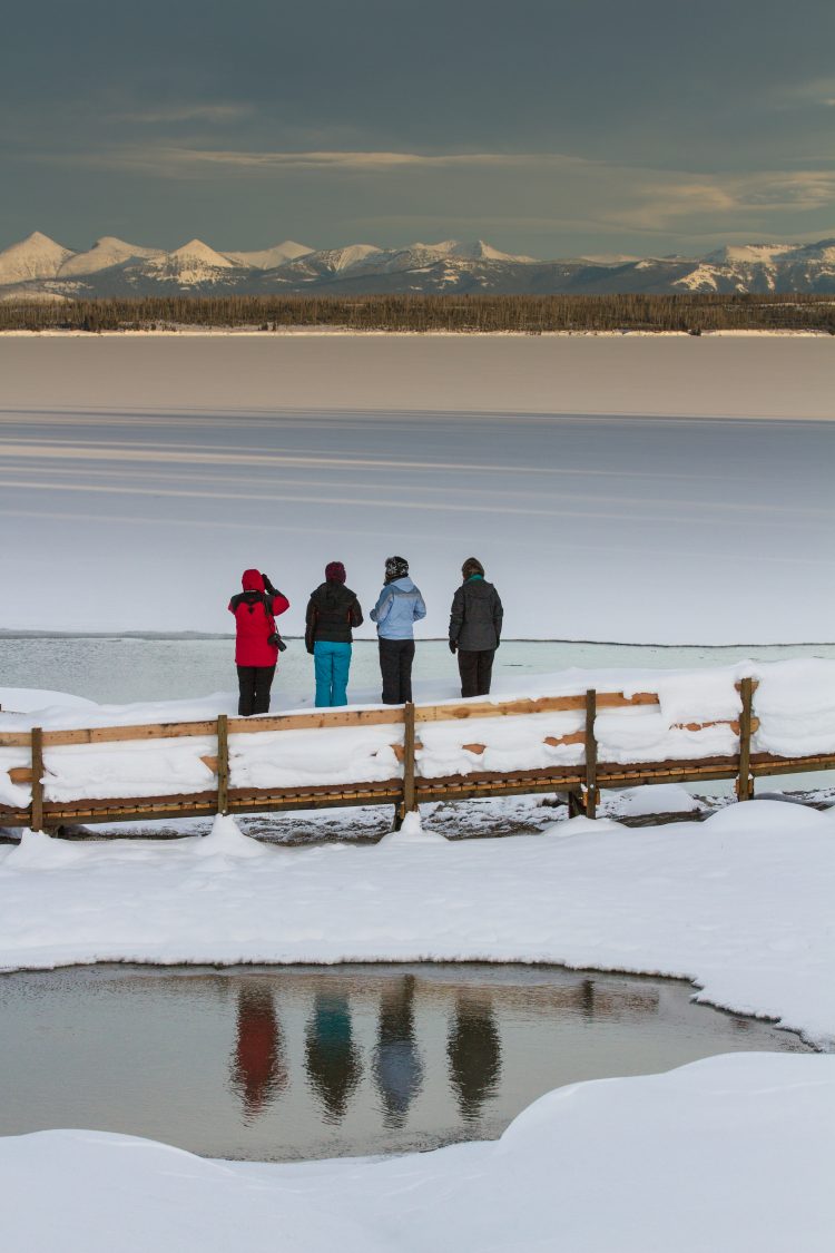 4 people overlooking a frozen lake, hot spring in foreground
