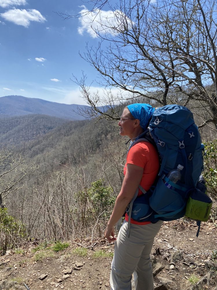 woman backpacker surveys a distant mountain range