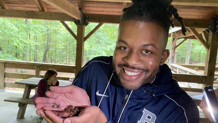Photo of a man smiling and holding a salamander