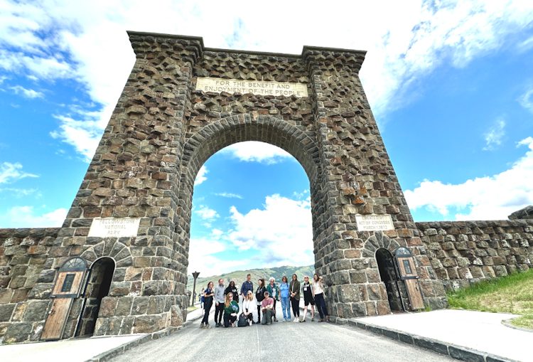 group standing under a stone arch with blue sky
