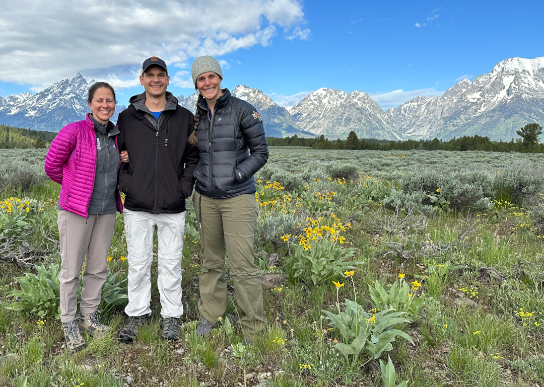 three people in front of mountains