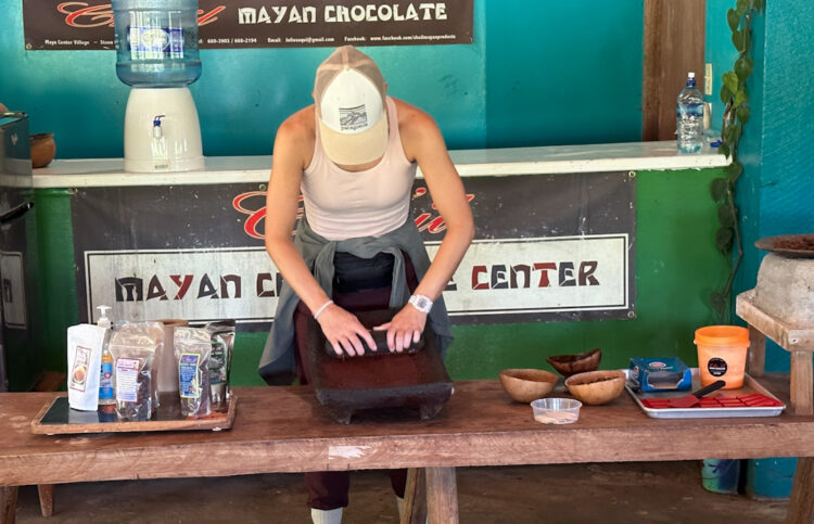 woman using tradiional grinding stone to crush cacao nibs into chocolate