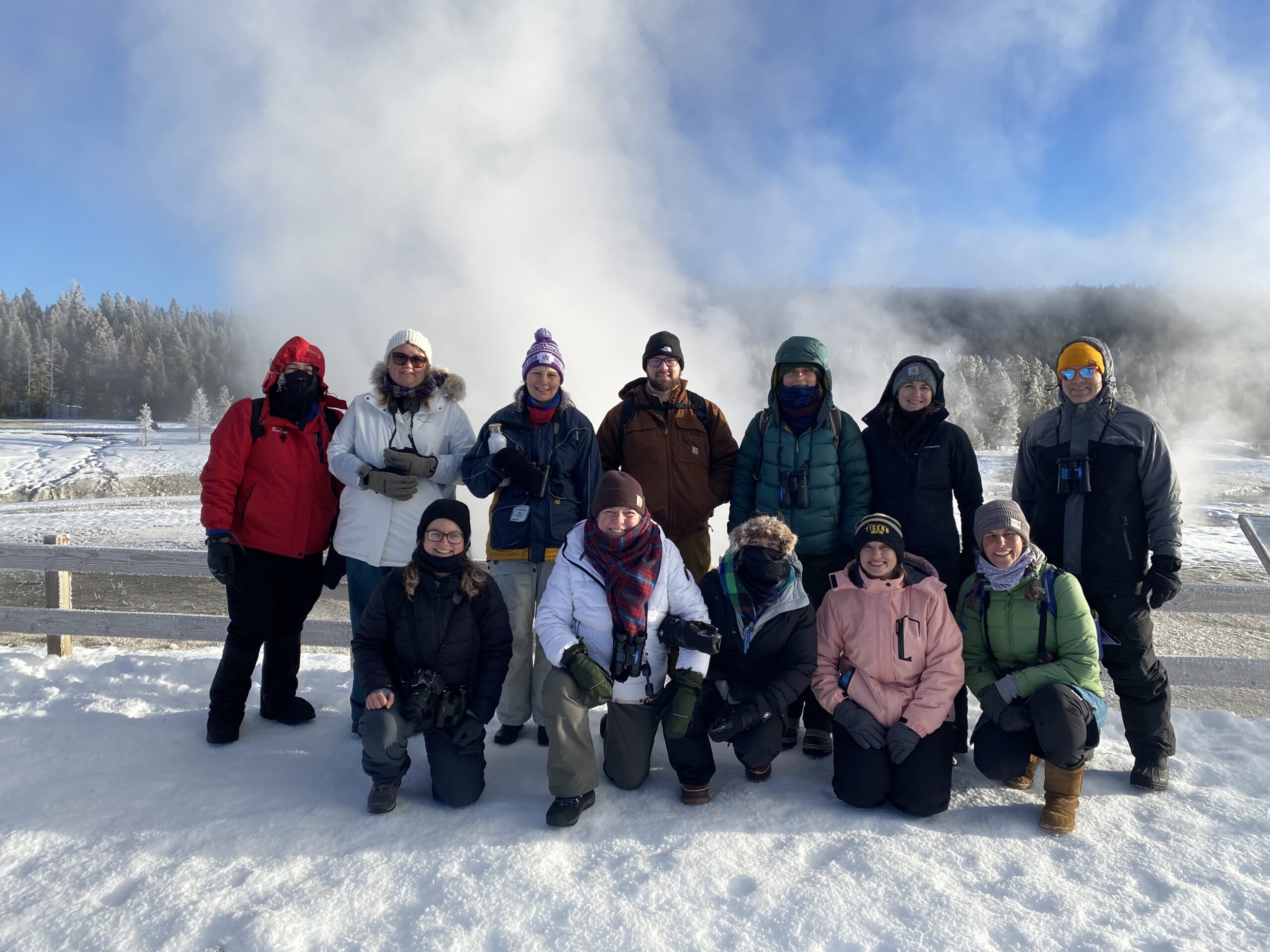 A group of people with steam behind them and snow below them