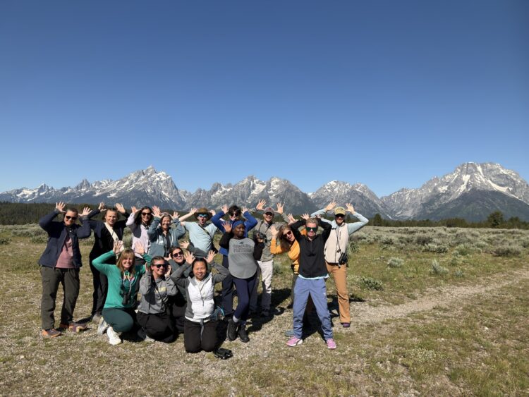 a group of teachers posing as moose in front of the Grand Teton mountain range