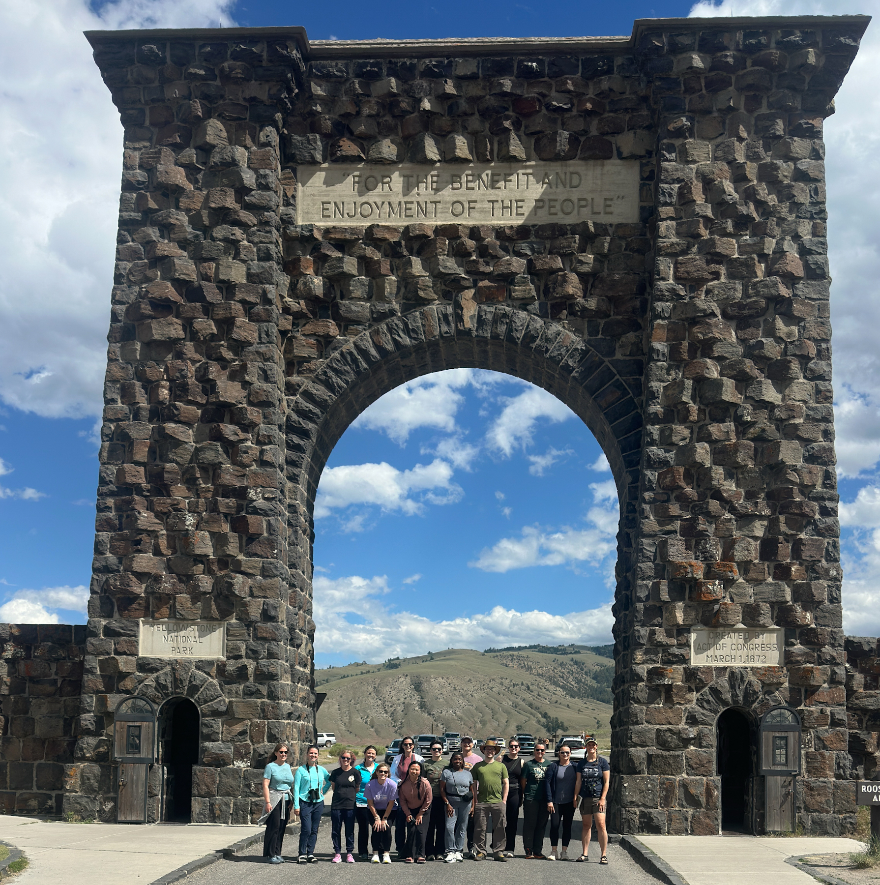 15 people standing under stone arch